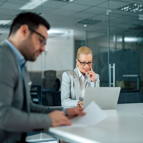 Professional translators reviewing certified documents in modern office setting with laptop and paperwork.
