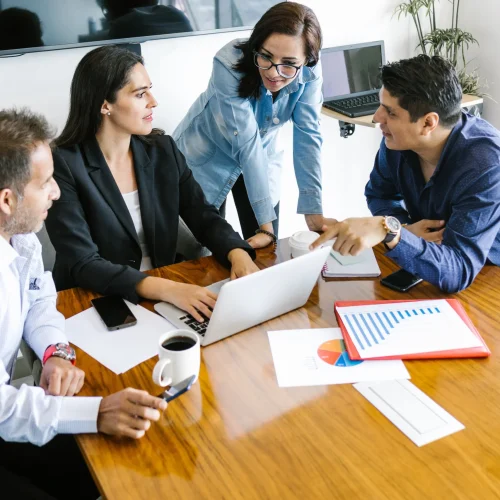 Professional team reviewing certified translation documents and business charts in collaborative office meeting.