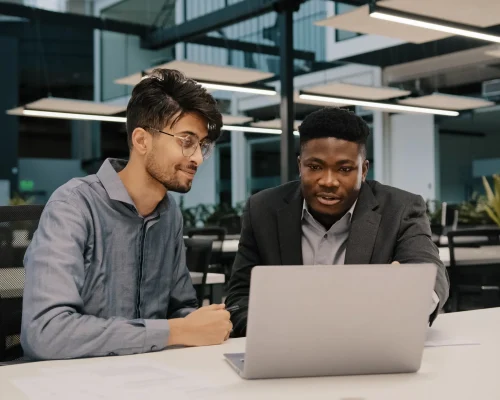 Professional team reviewing documents on laptop in modern office setting during business meeting.
