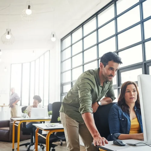 Professional team collaborating in modern office with computer workstation and natural lighting.
